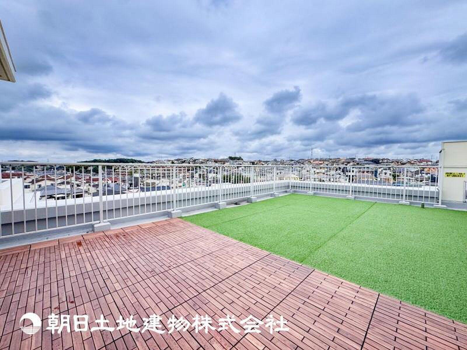 デッキと芝の二層、その先に街の屋根と空が広がる