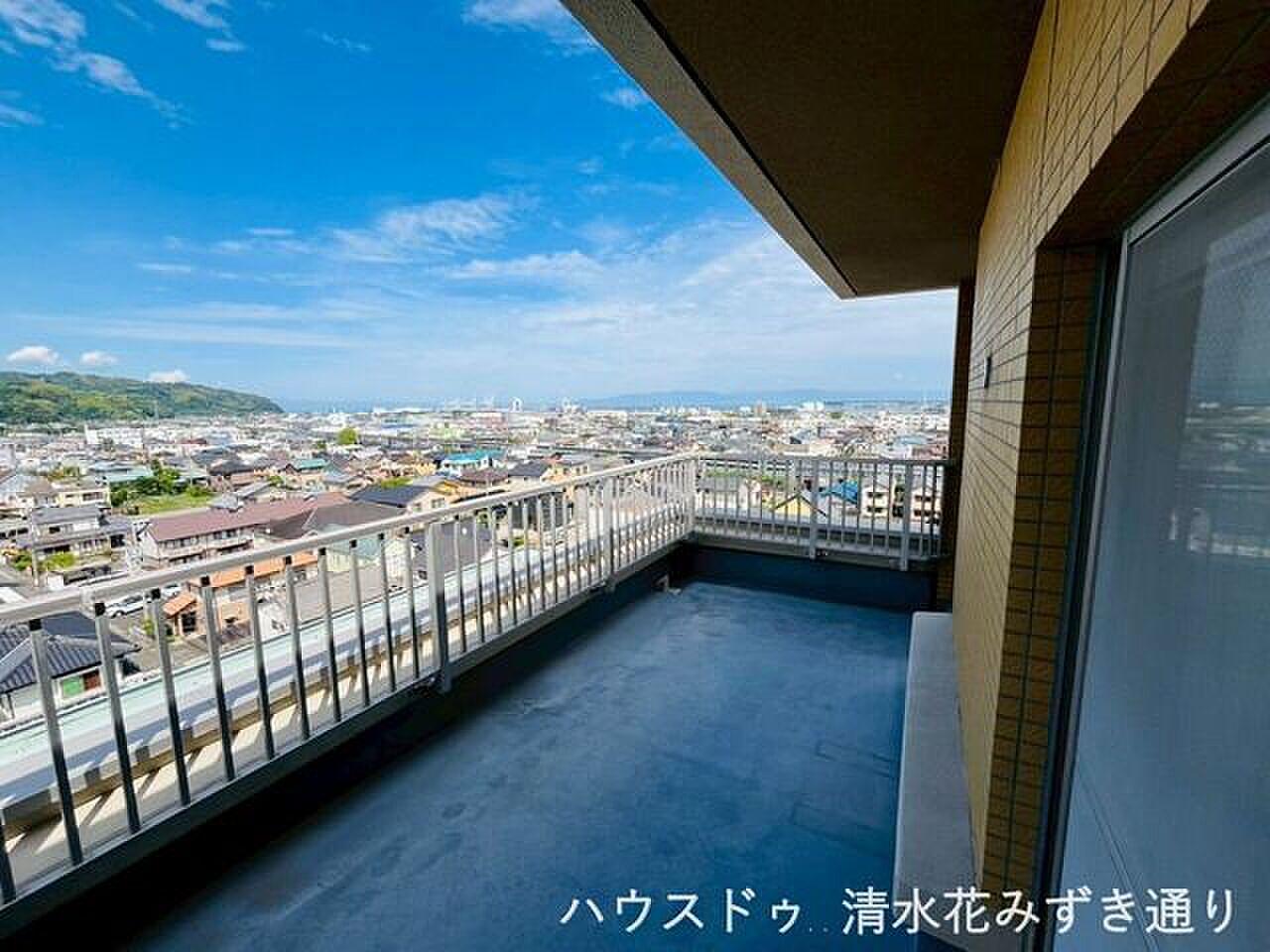 最上階の角、手すりの向こうに山並みと街がひと続き