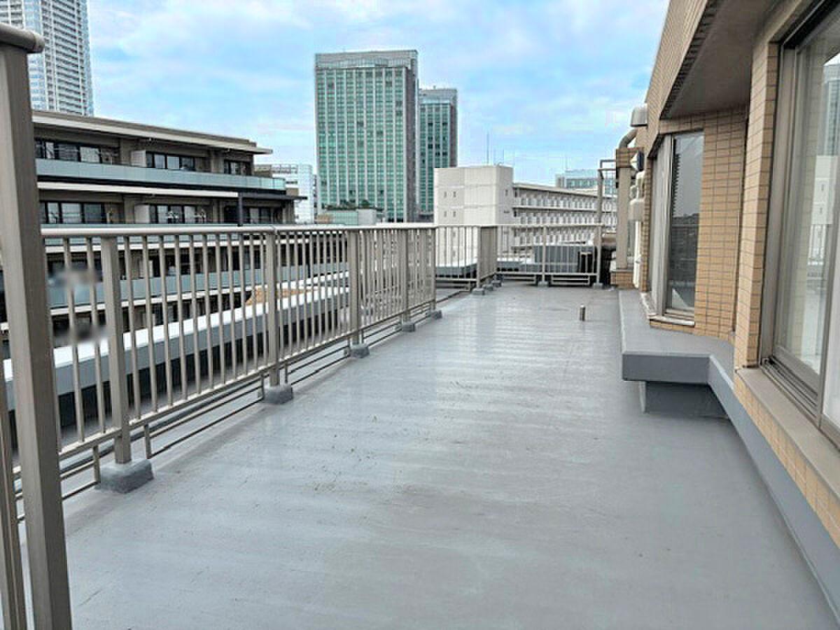 8階建て最上階、31.3㎡の空。手すりの向こうに街並みと遠くのタワーが並ぶ、まっすぐ長い屋外の廊下